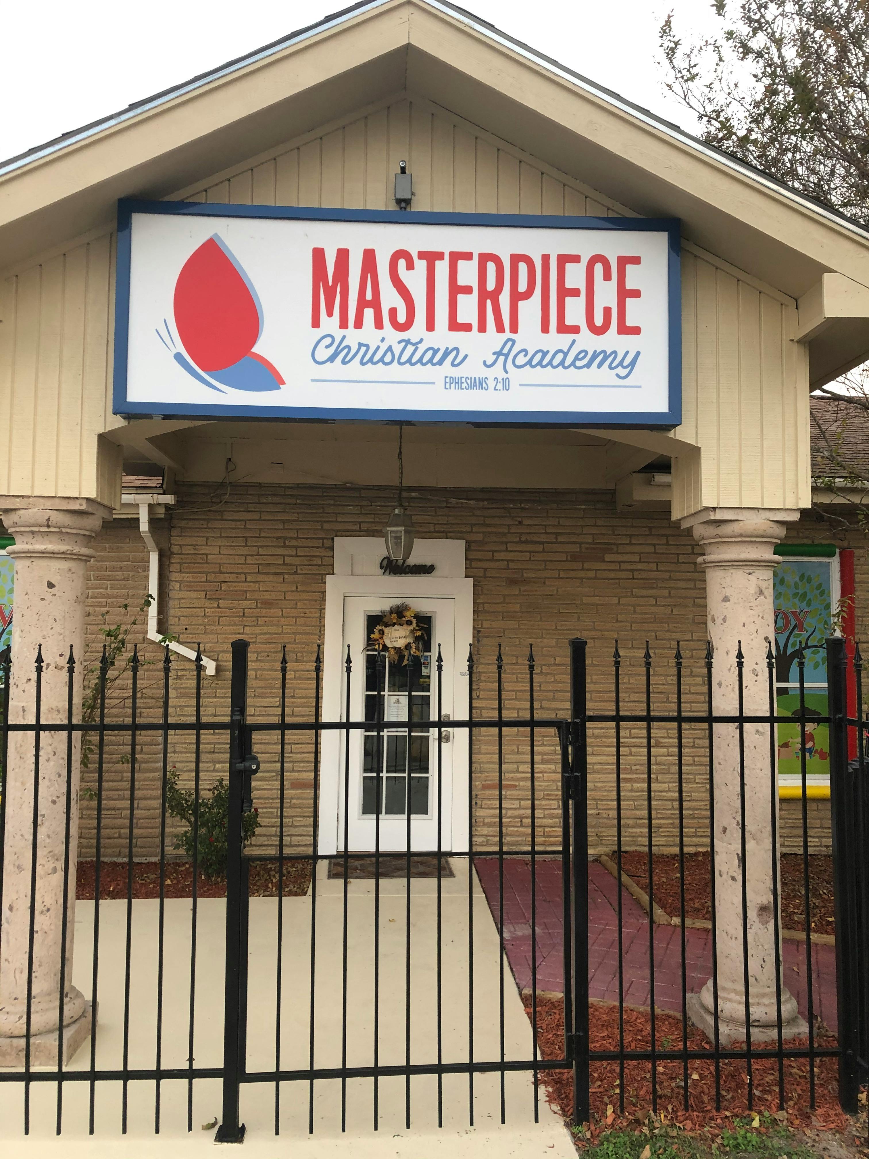 Masterpiece Christian Academy sign above a building entrance with a black fence