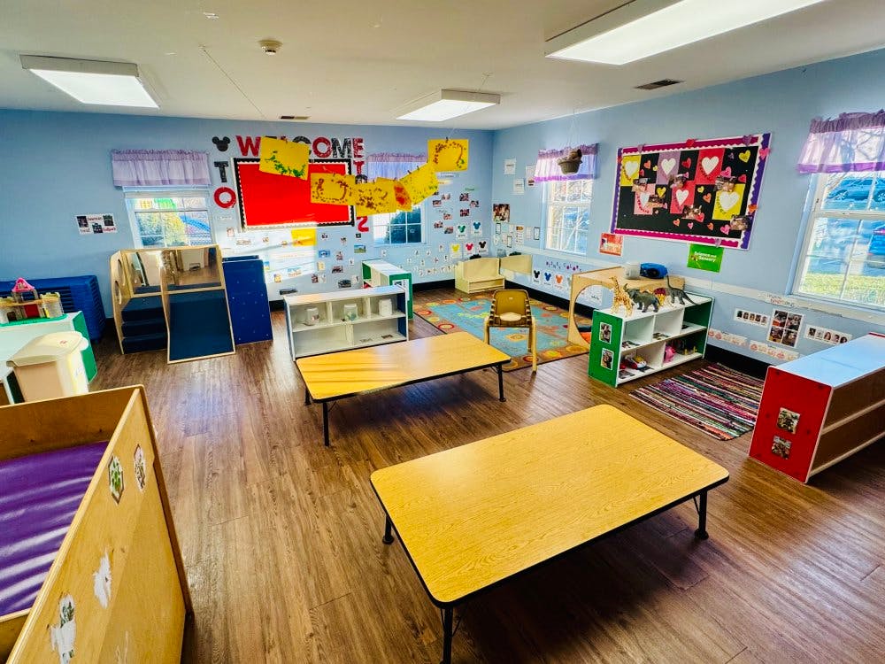 An empty early childhood classroom with various play areas and small tables