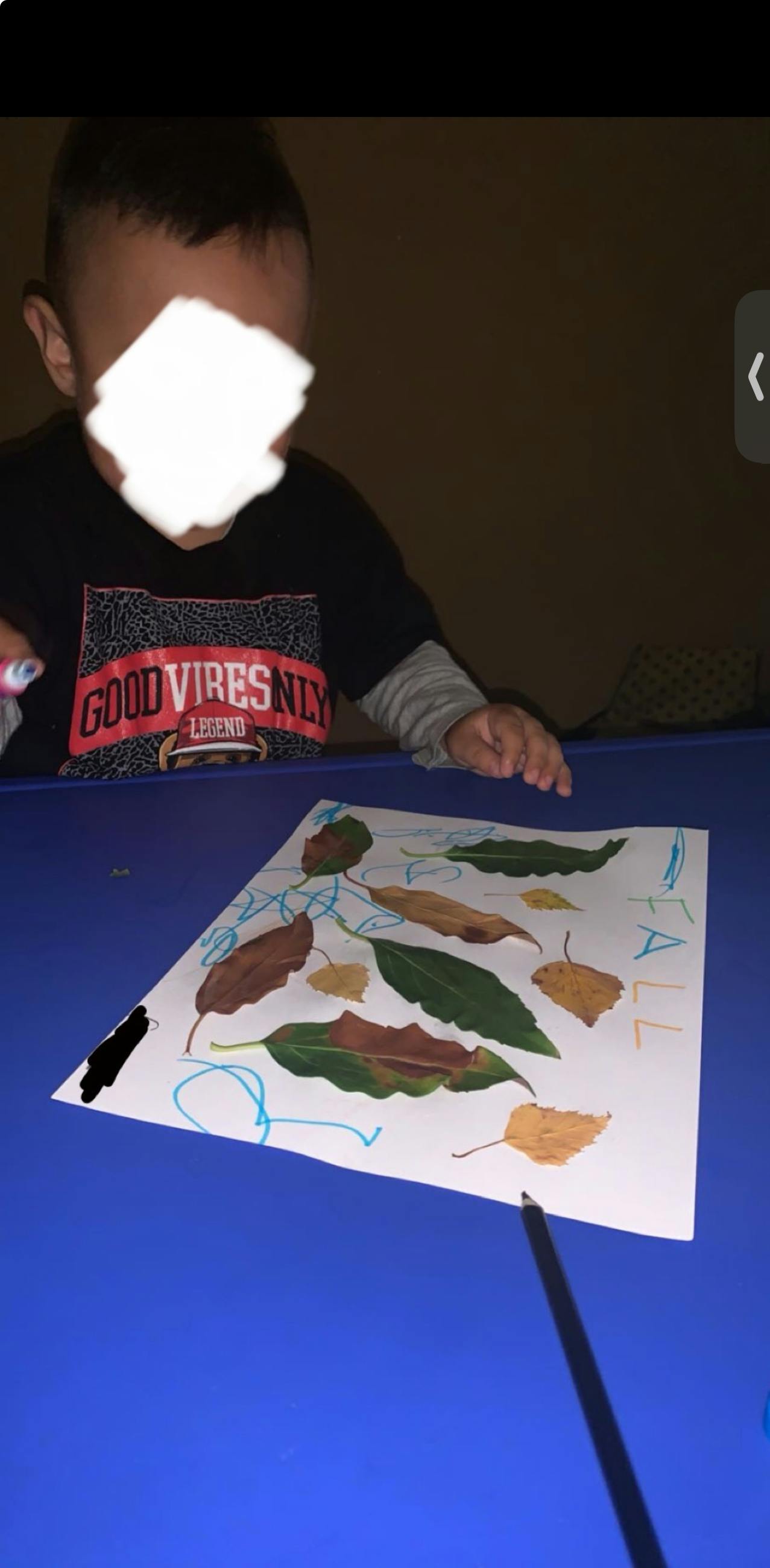 Child drawing on paper with leaves