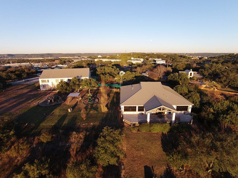 Aerial view of two houses with gray roofs surrounded by trees