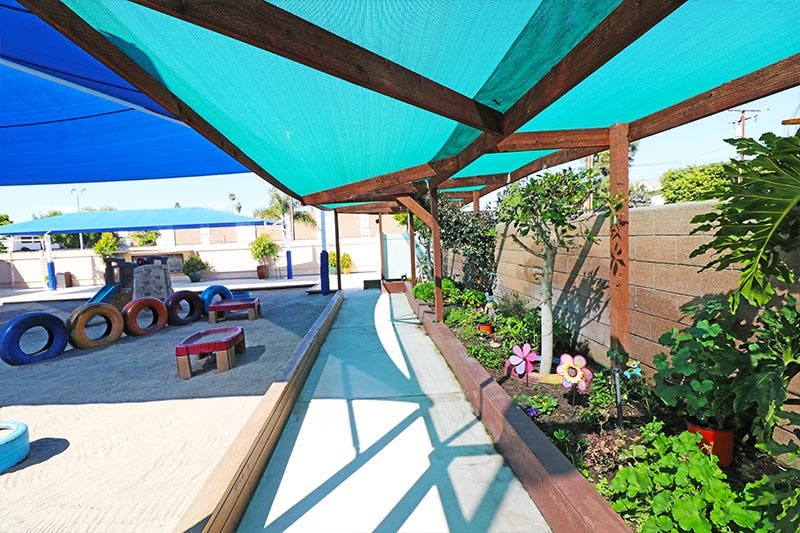 Outdoor play area with shade structures and a garden