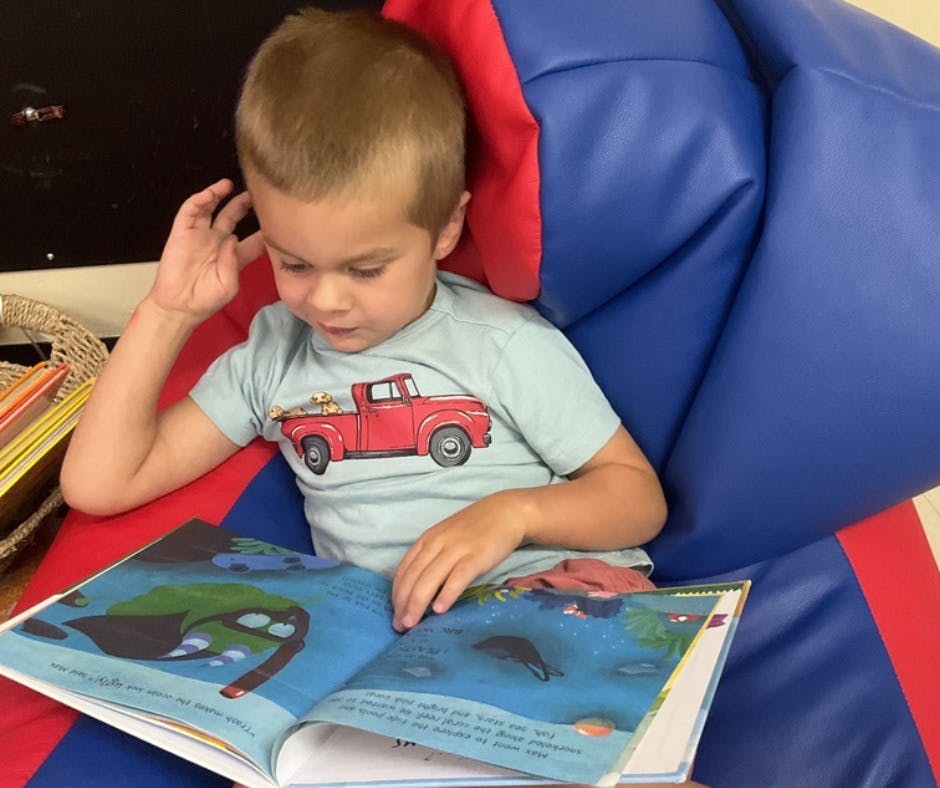 Child sitting in a chair reading a book