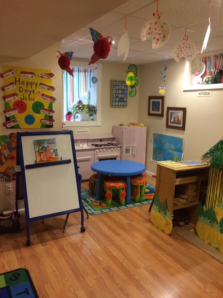 Playroom with a small blue table and chairs, toy kitchen, and whiteboard