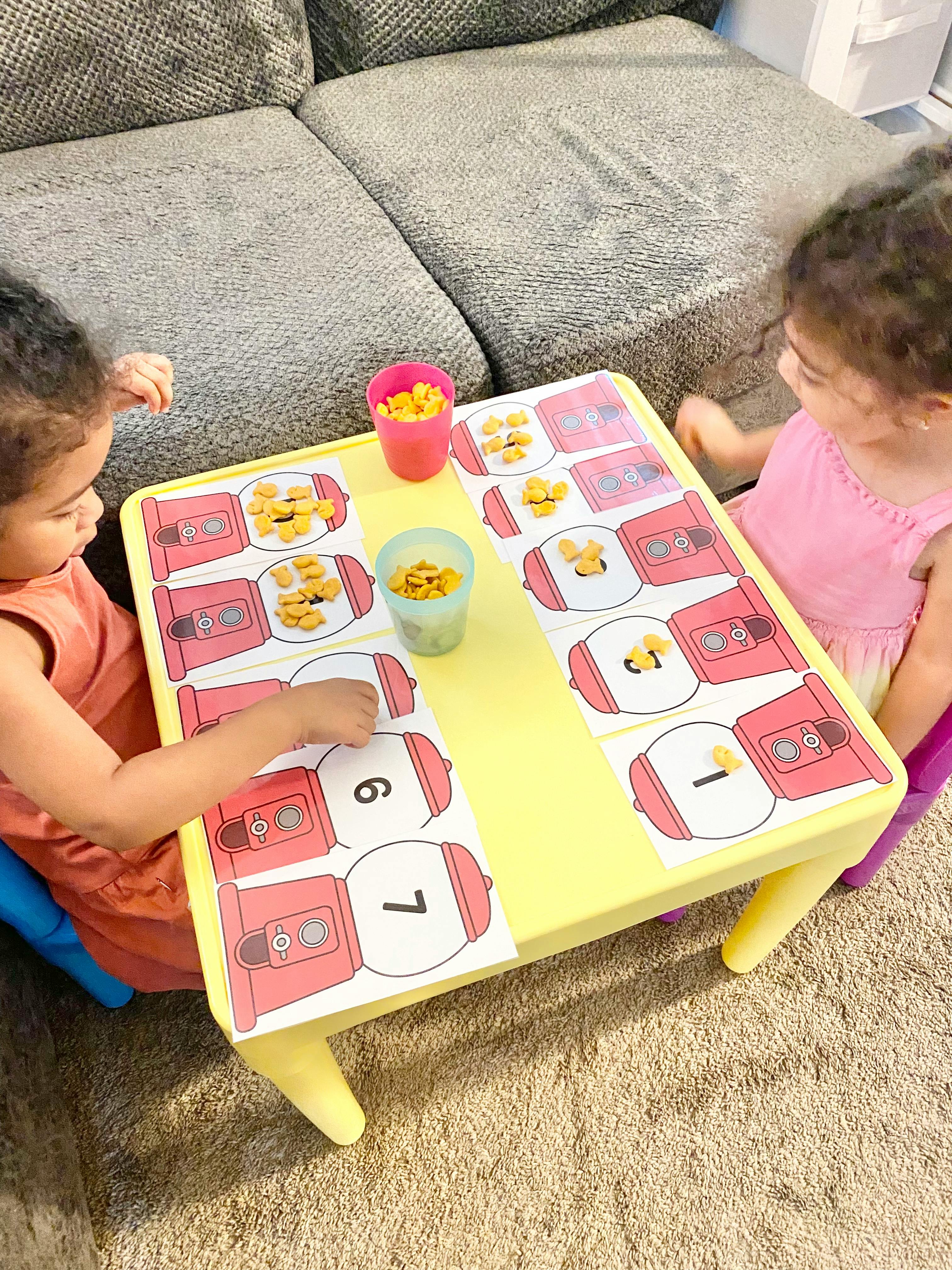 Two children playing with a counting game on a yellow table