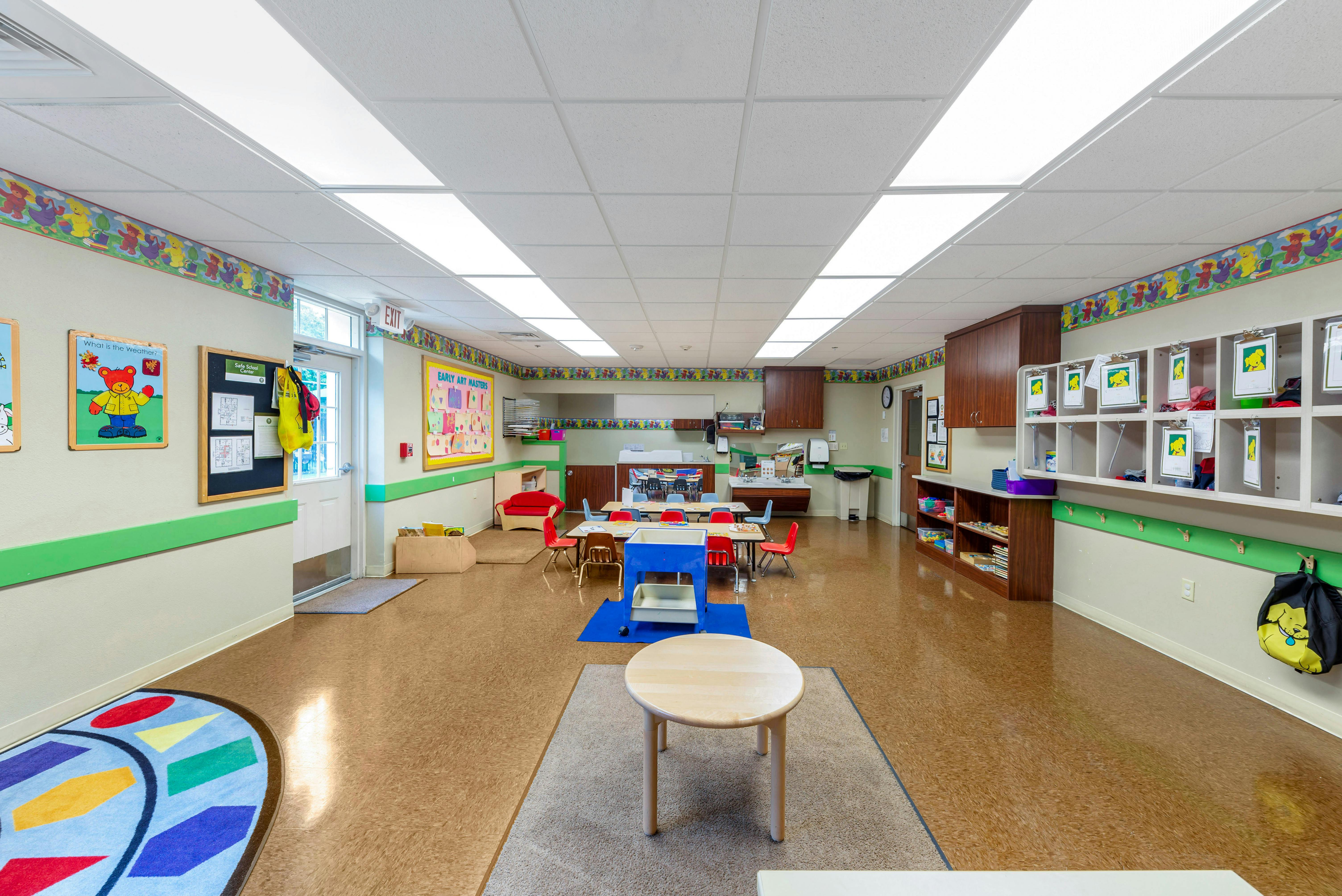 An empty early childhood classroom with small tables, chairs, and shelves