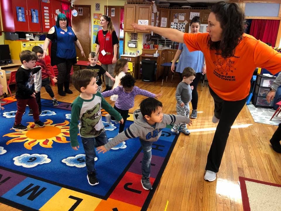 Adult and children in a classroom doing a balancing exercise