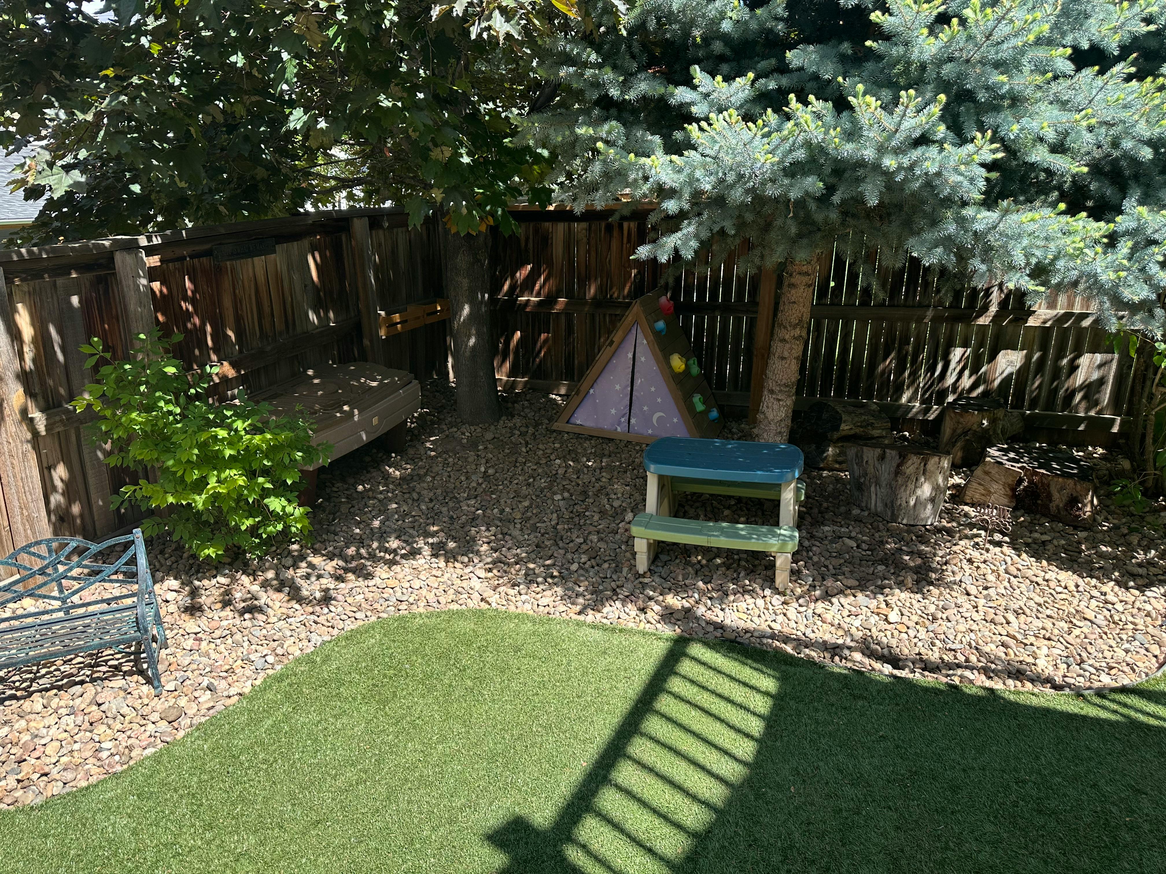 Backyard play area with artificial turf, gravel, and wooden fence