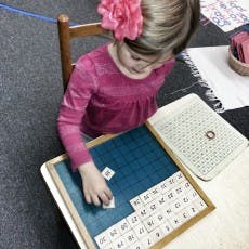 Child working with number tiles on a board