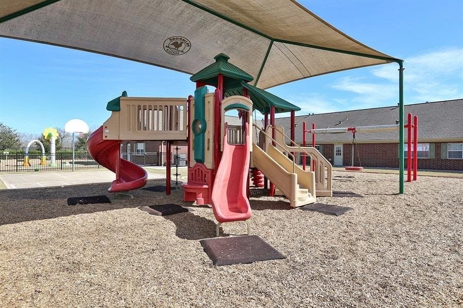 Playground with slides and climbing structures under a shade canopy