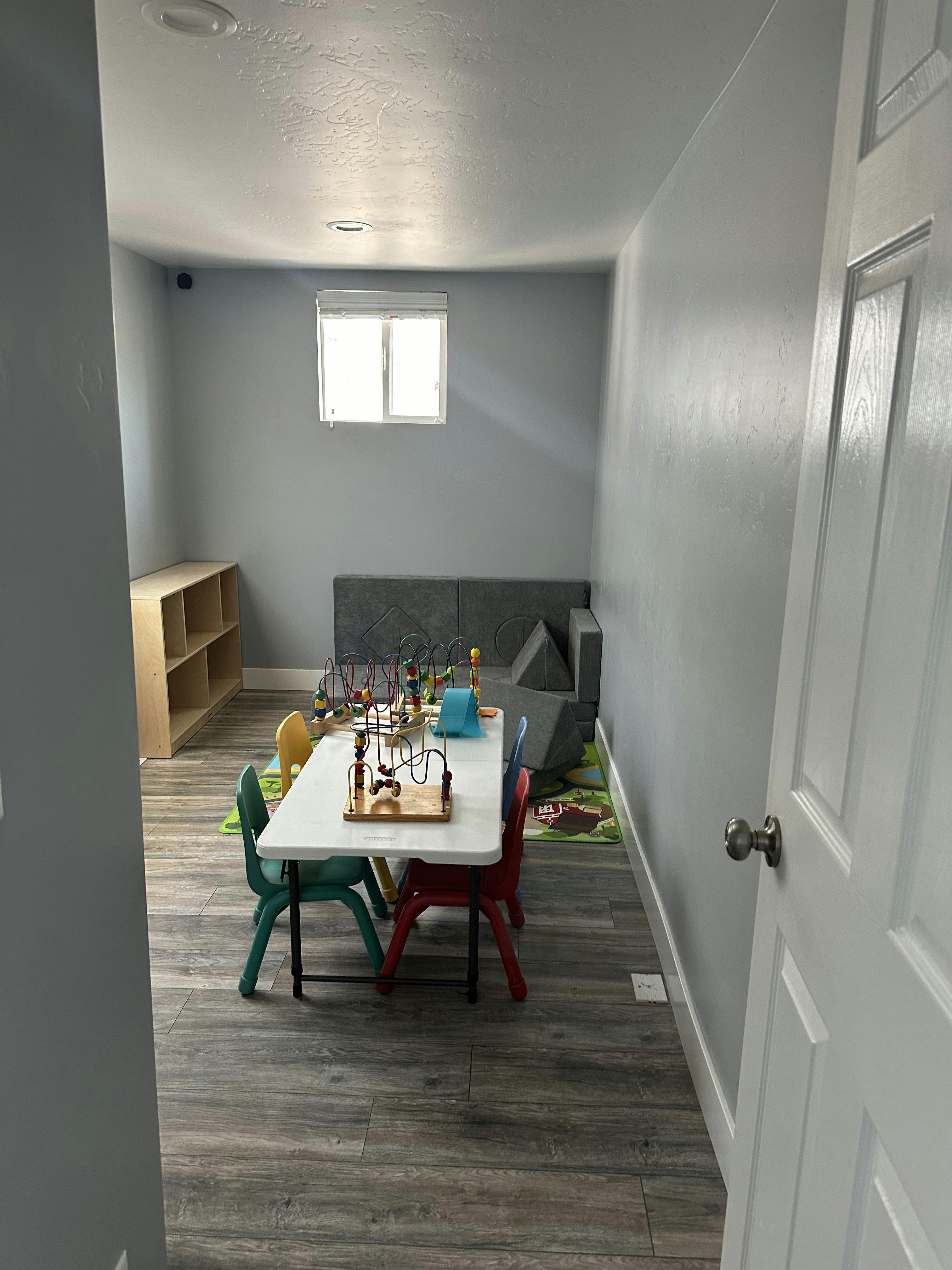 Playroom with a small table and chairs, toys, and a gray sofa