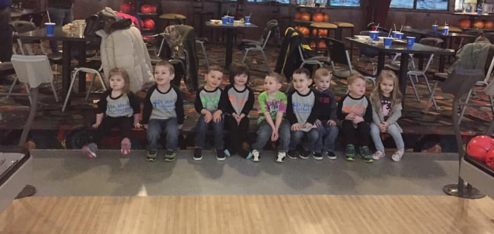 Group of children sitting in a row at a bowling alley