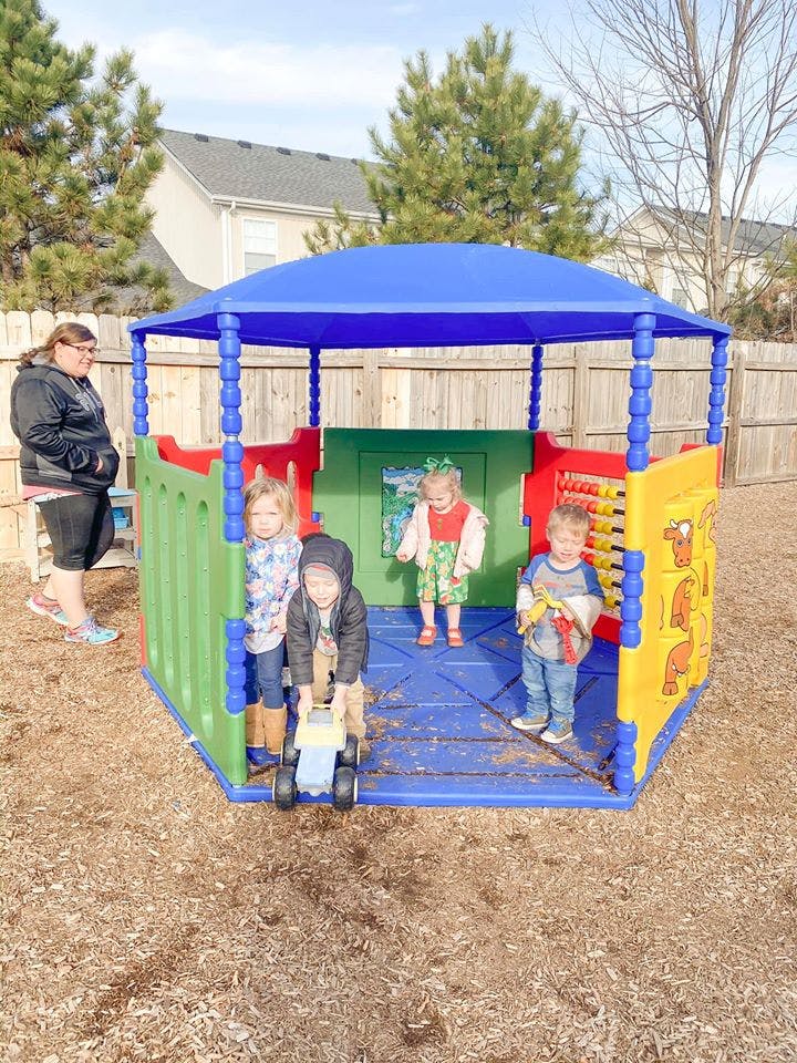 Adult and children playing in a colorful outdoor playhouse