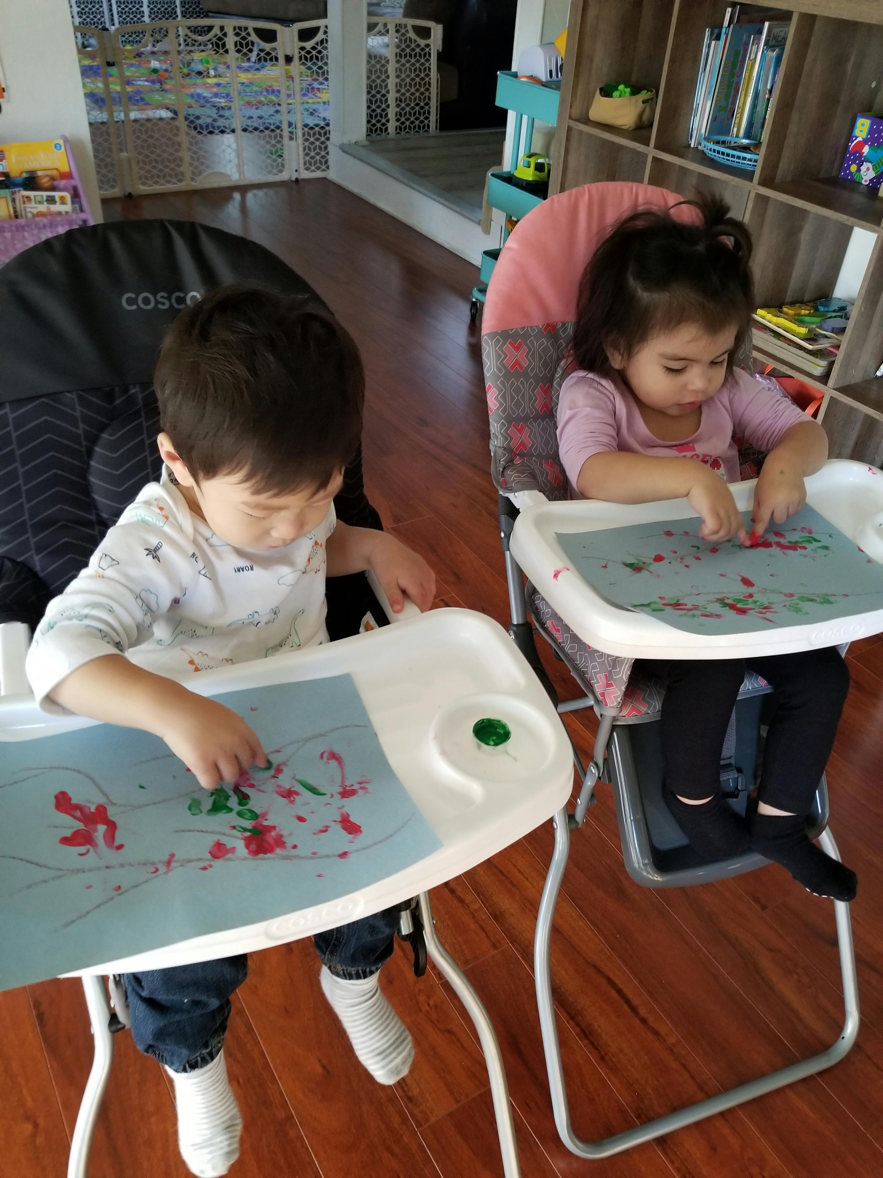 Two children in high chairs finger painting