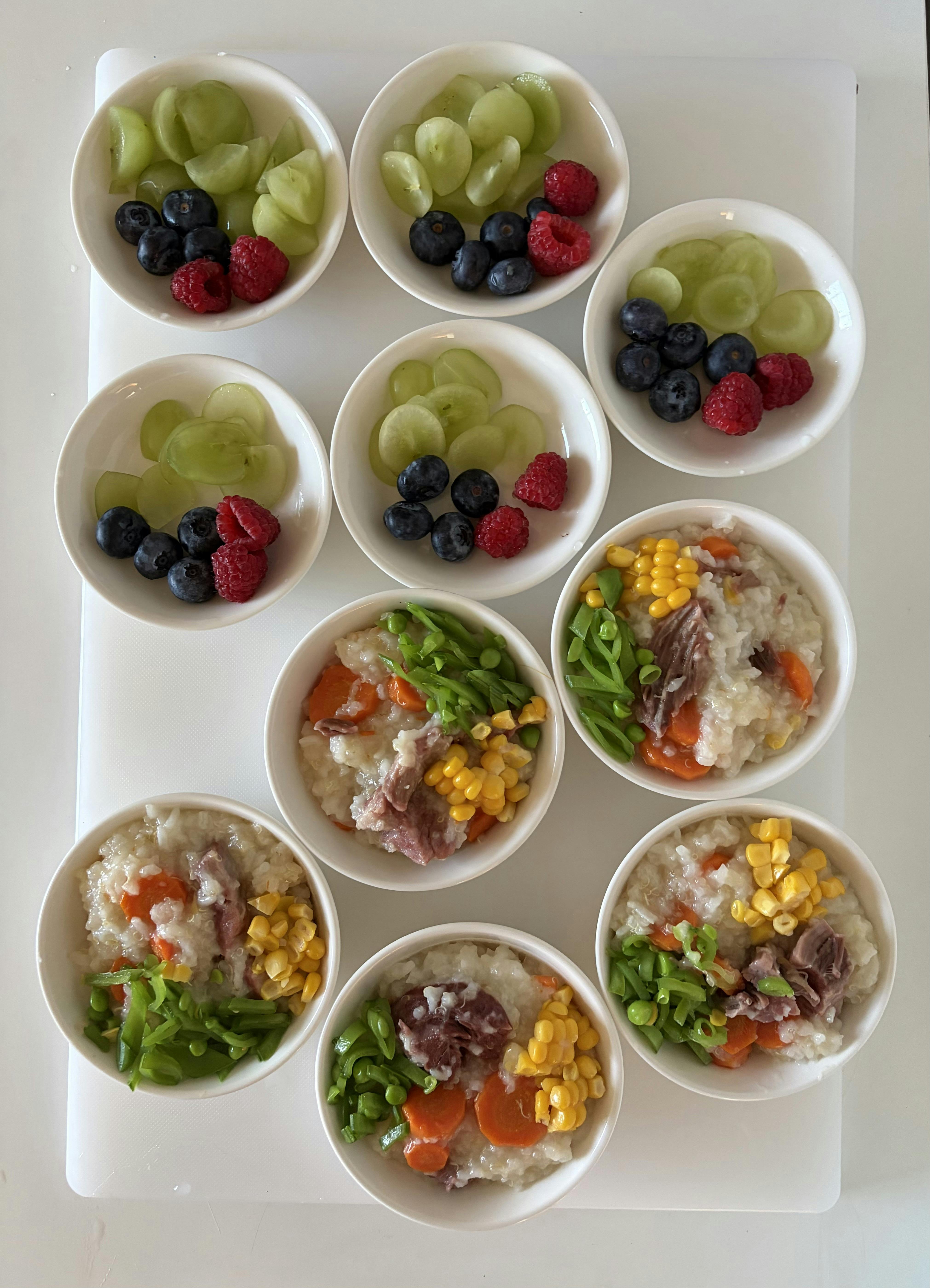 Small bowls filled with fruit and bowls filled with rice, meat, and vegetables