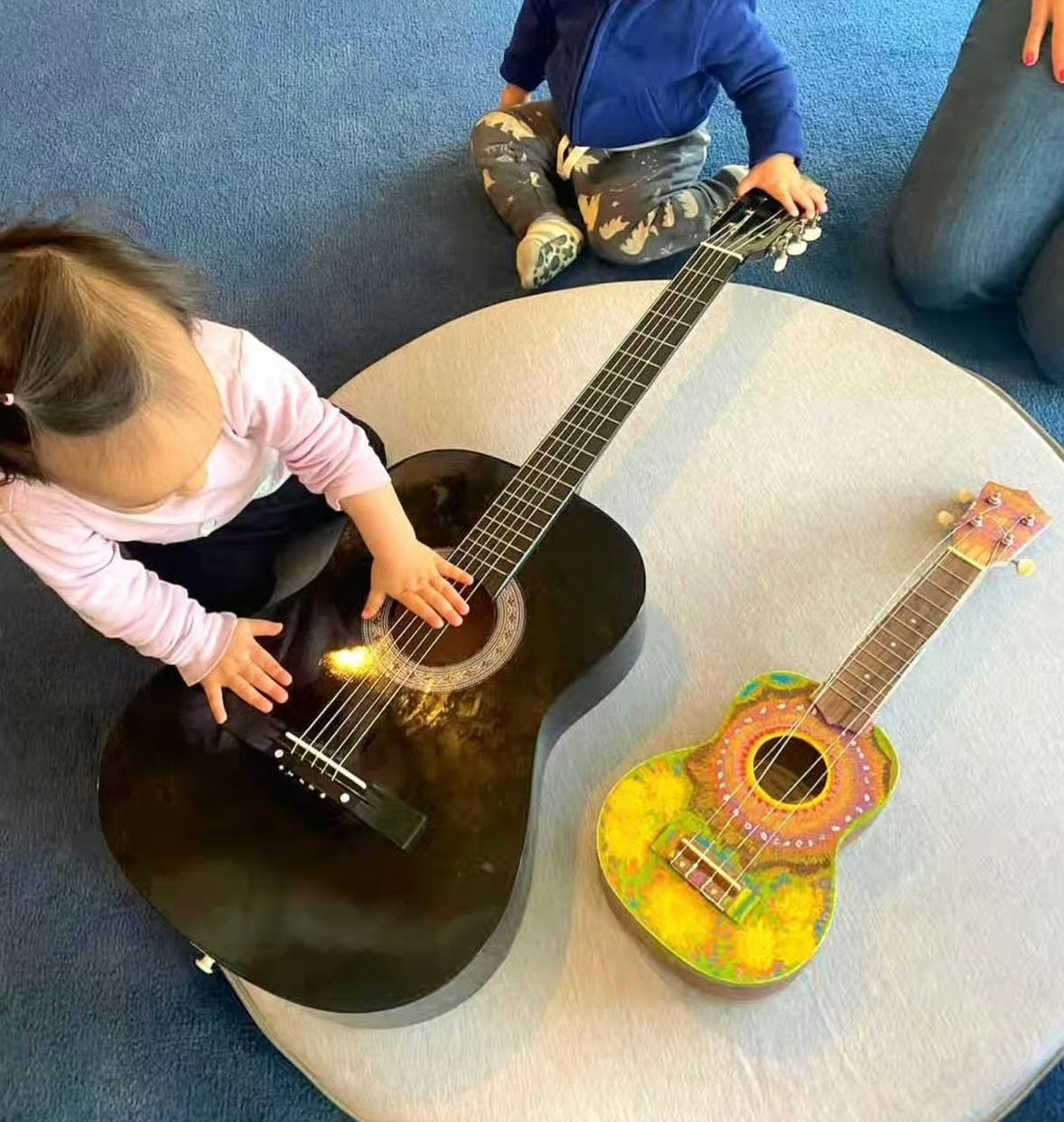 Child playing a guitar, another child nearby