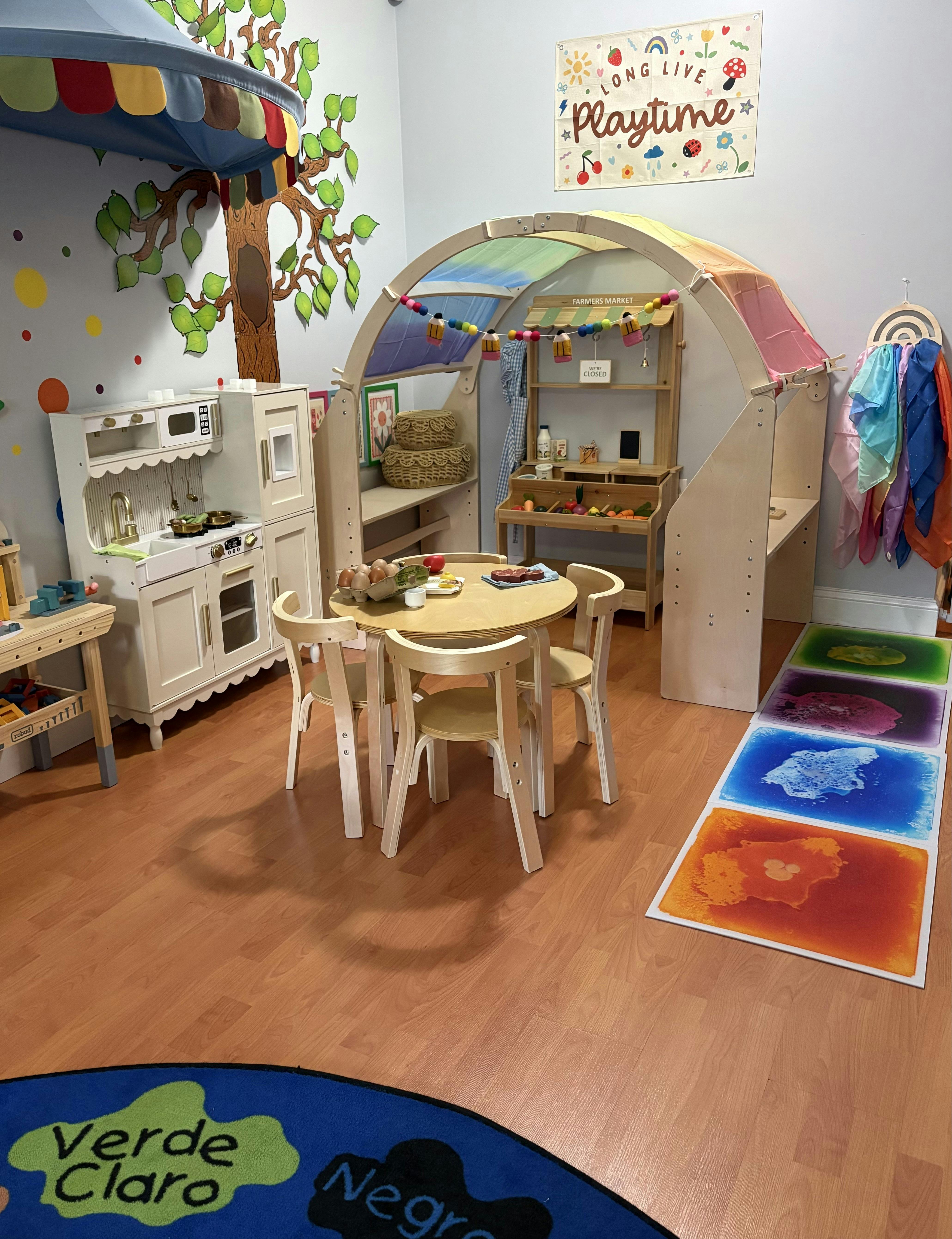 Playroom with a toy kitchen, a market stall structure, and a child-sized table