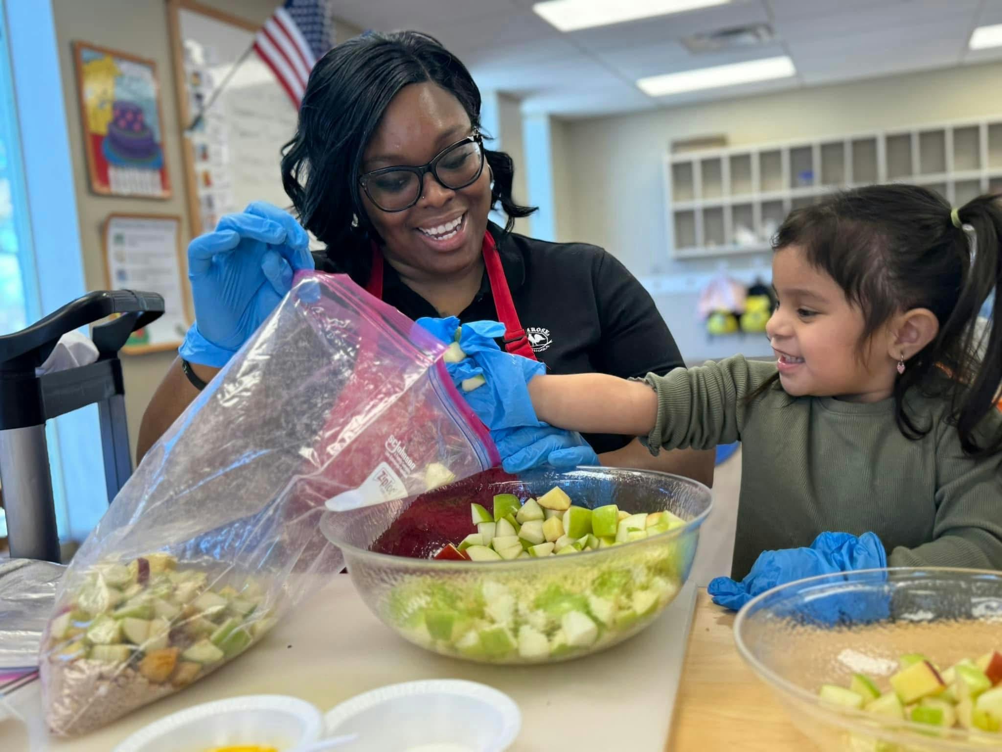 Adult and child wearing gloves, mixing fruit in bowls