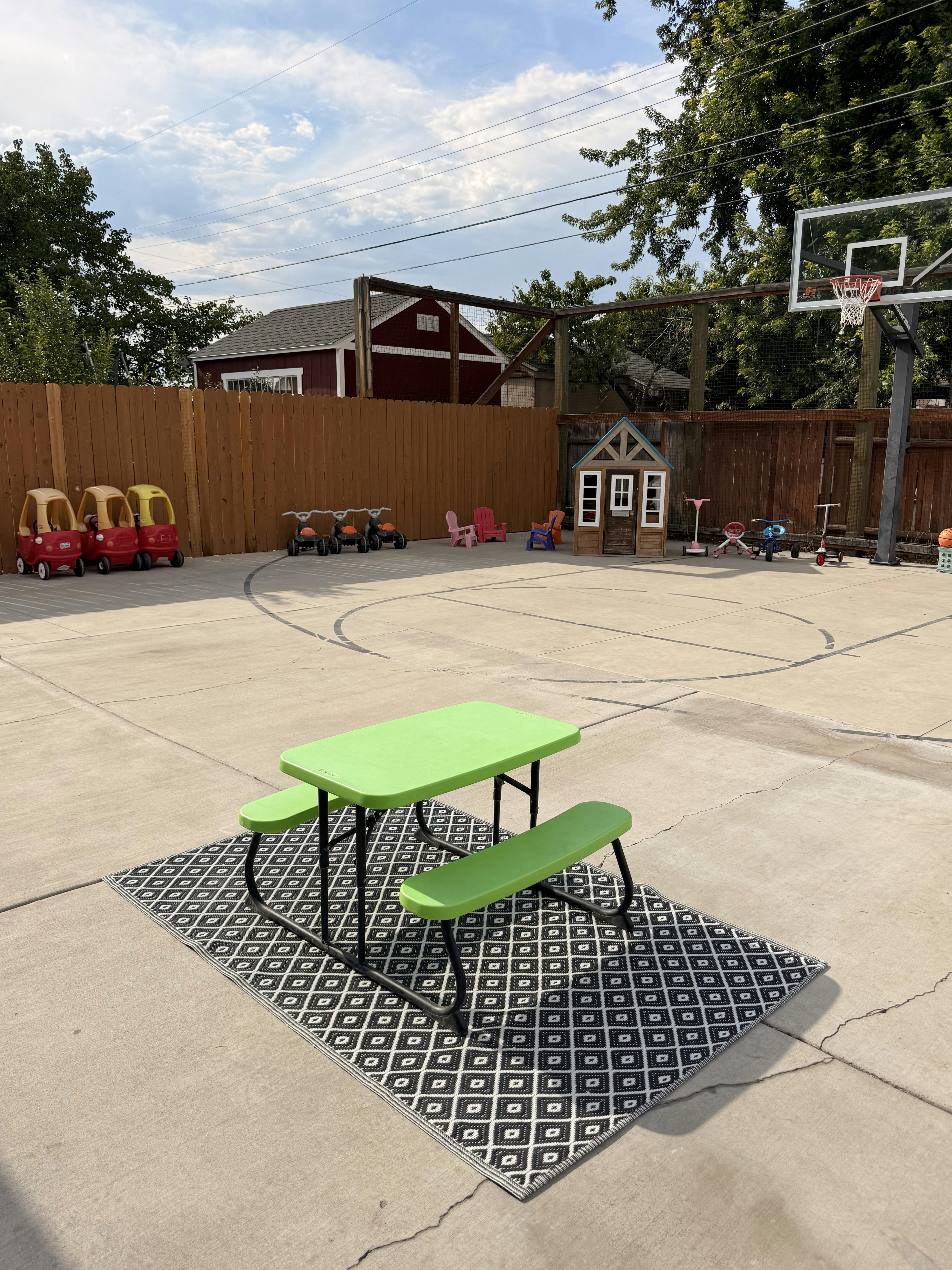 Small table and benches on a patterned rug in a backyard playground