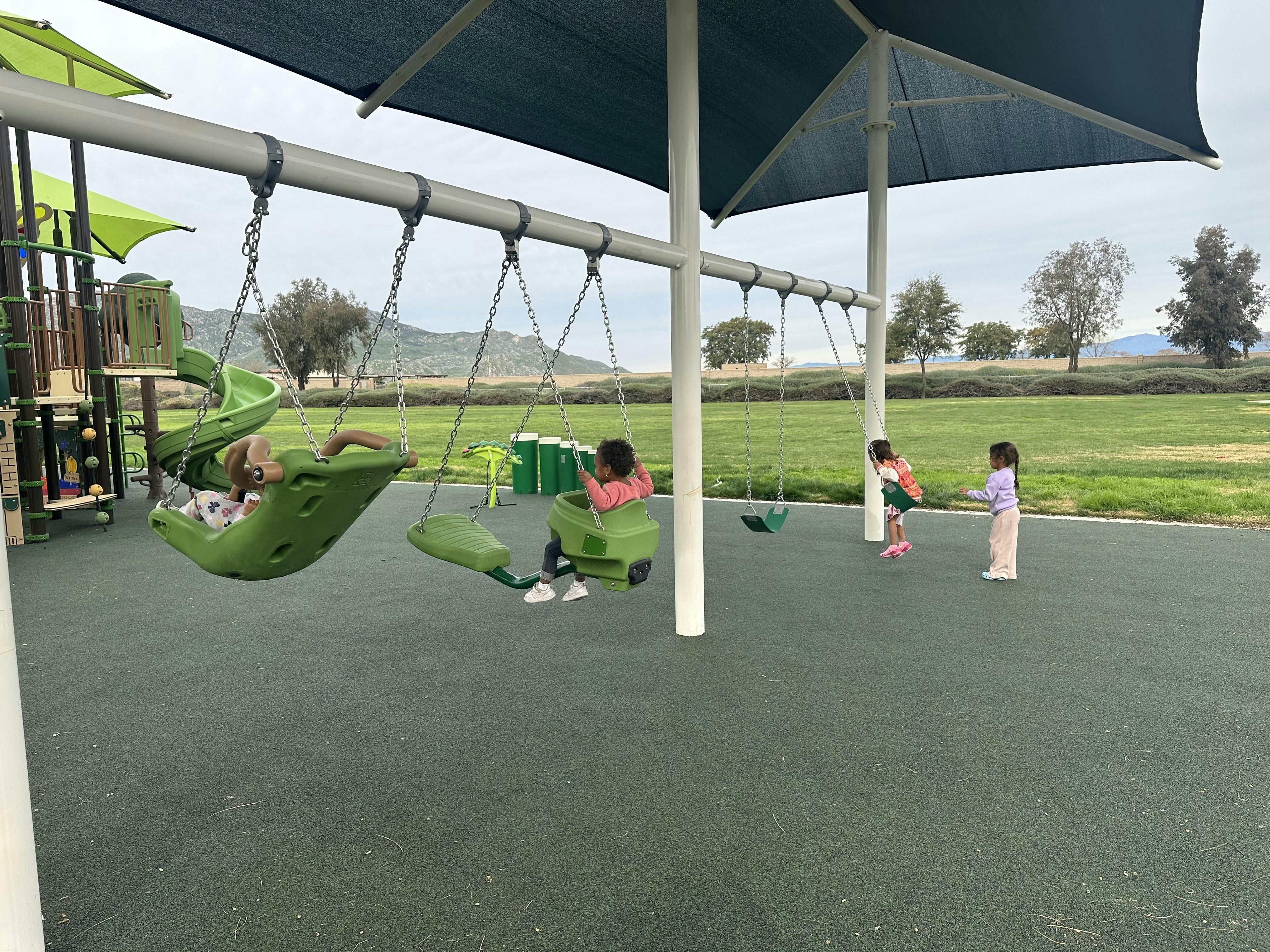 Children playing on swings and standing on a playground