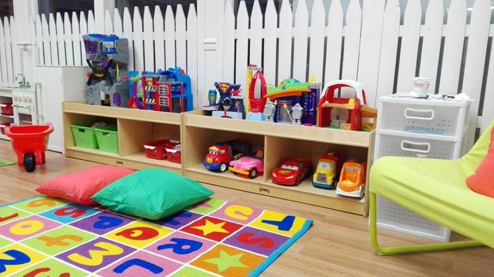 Playroom with toys on shelves, colorful rug, and cushions
