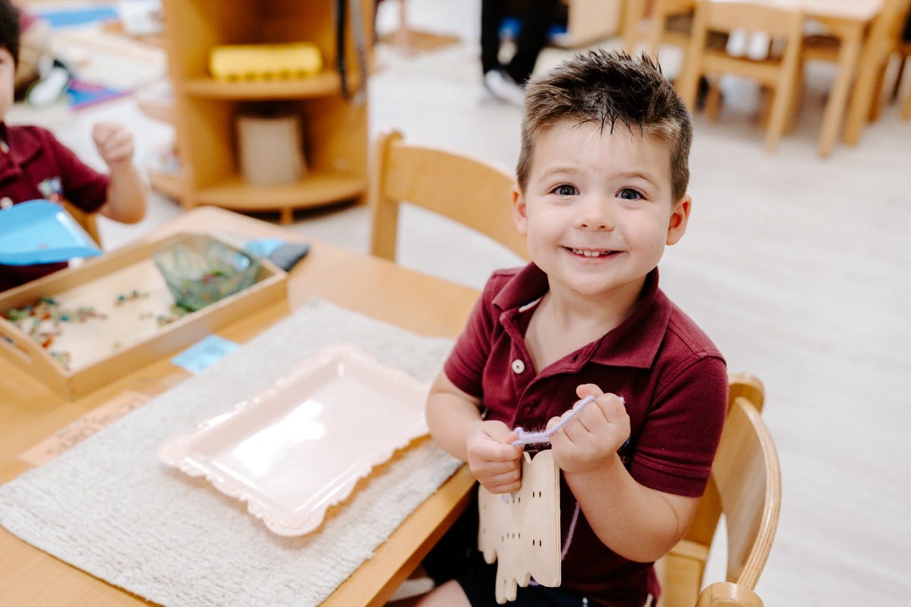Child sitting at a table holding a craft project