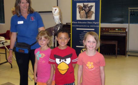 Adult and three children posing with an owl