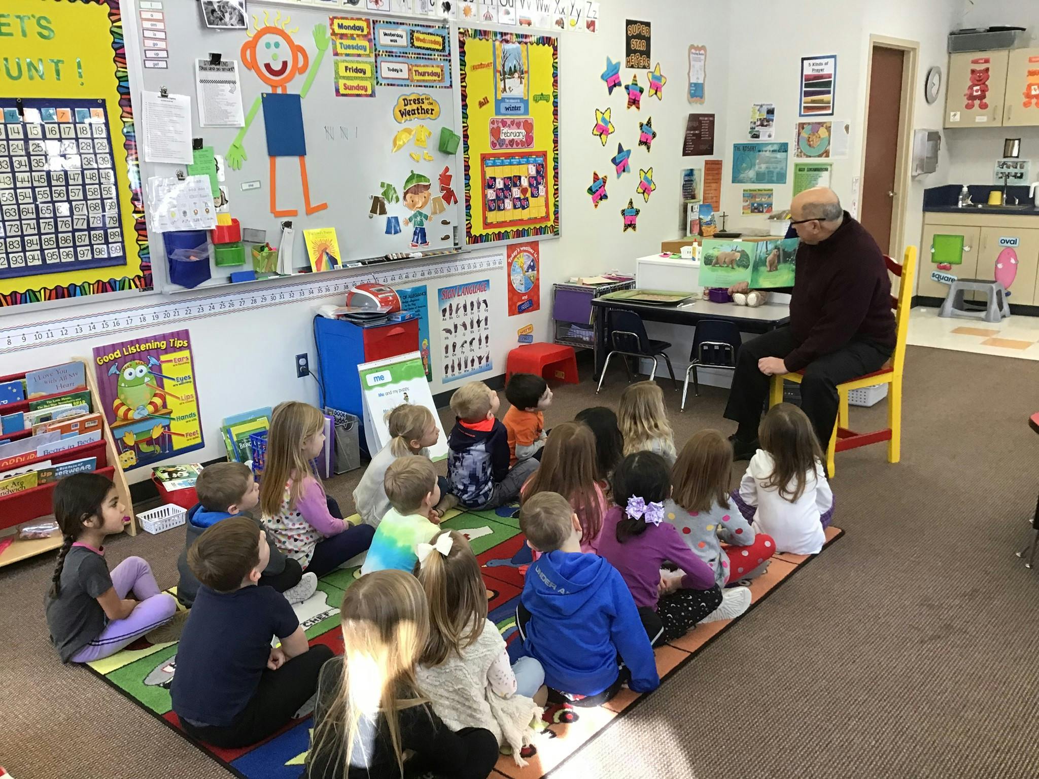 Adult person reading to a group of children in a classroom