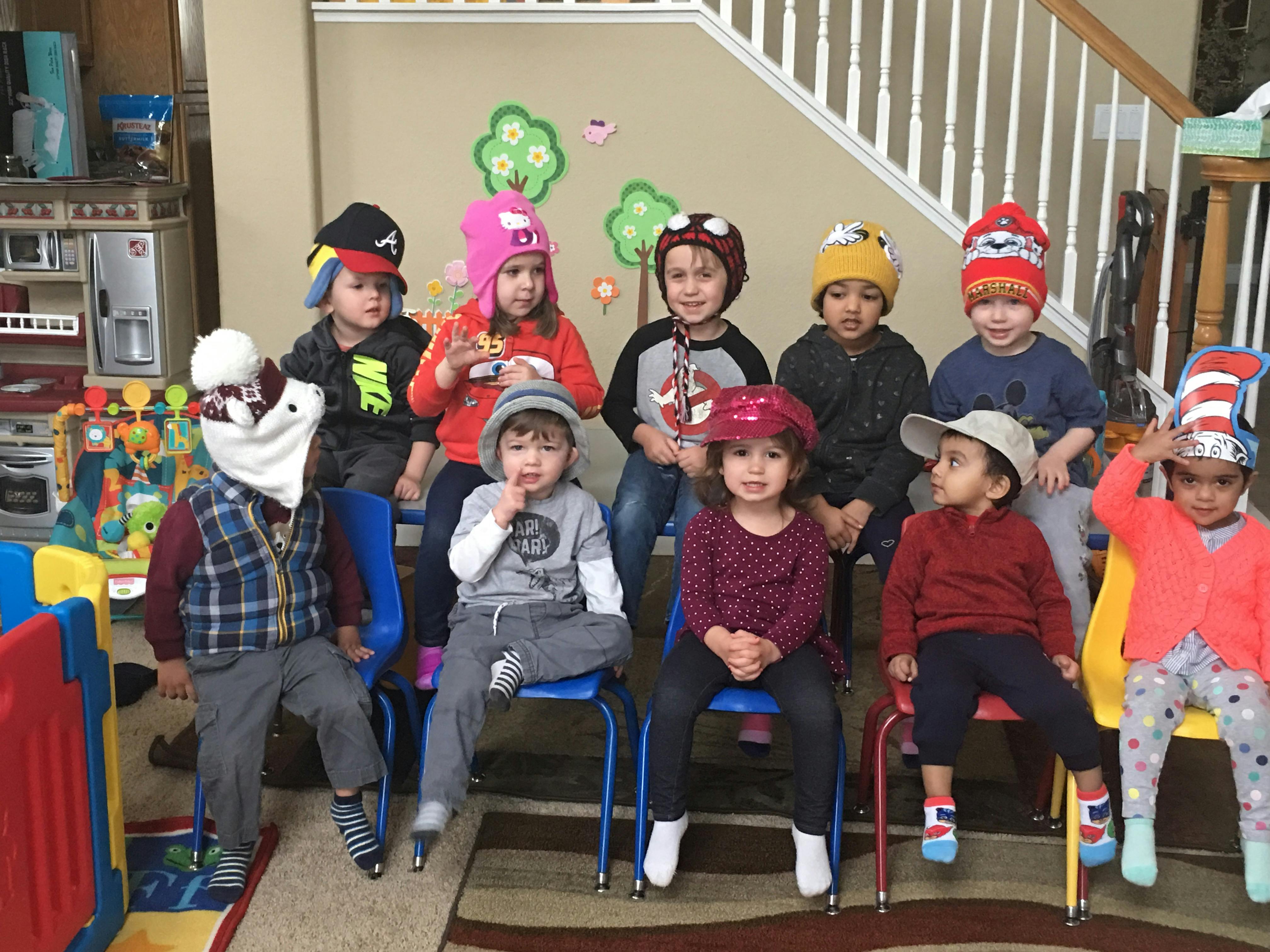 Group of children wearing hats, some sitting on chairs