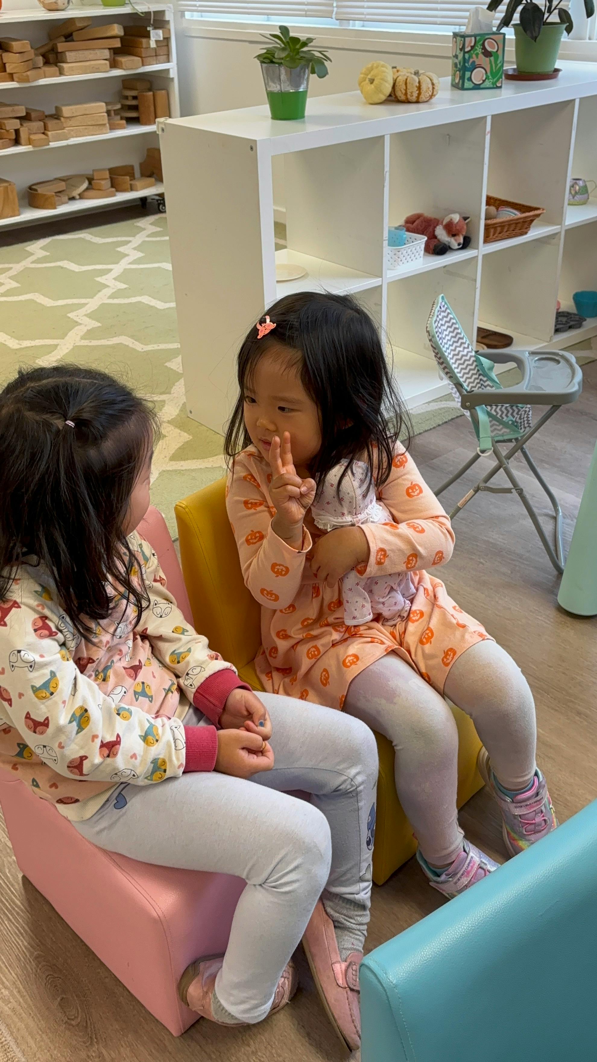 Two children sitting on chairs facing each other