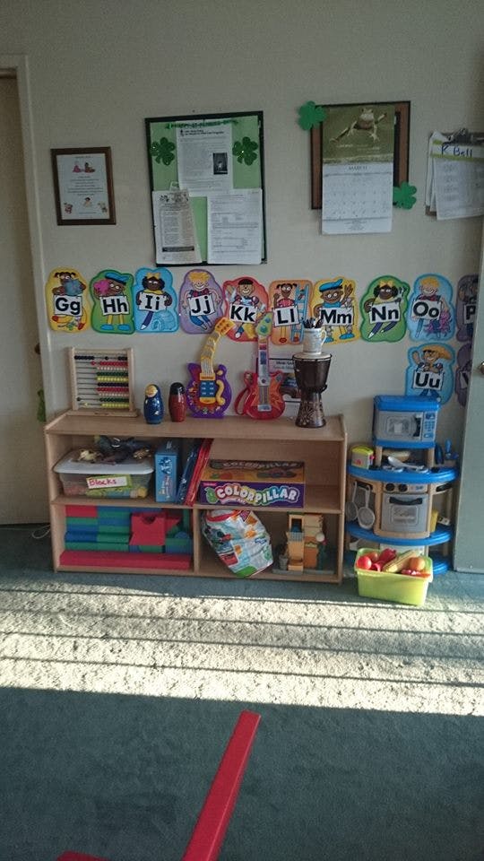 Classroom with alphabet cutouts, a bookshelf with toys, and a play kitchen