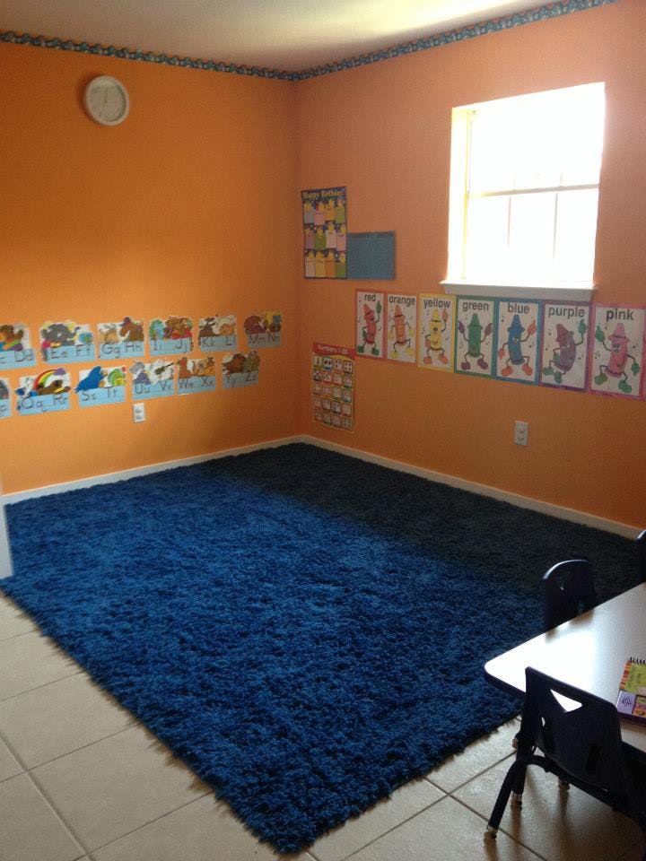 Classroom with orange walls, blue rug, and educational posters