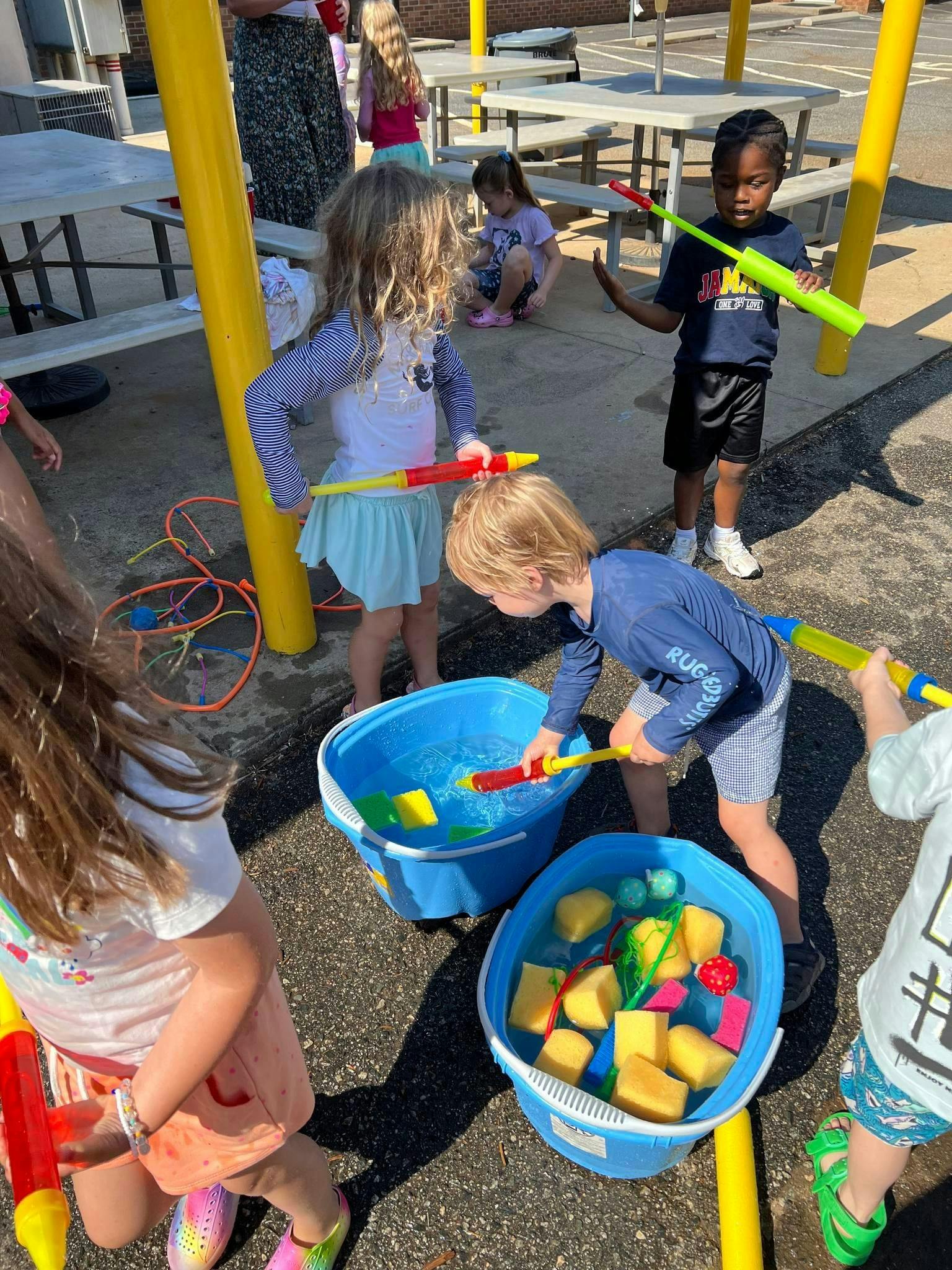 Children playing with water toys and buckets outdoors