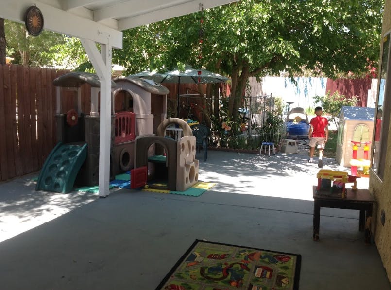 Child standing in a backyard play area with playhouses and slides