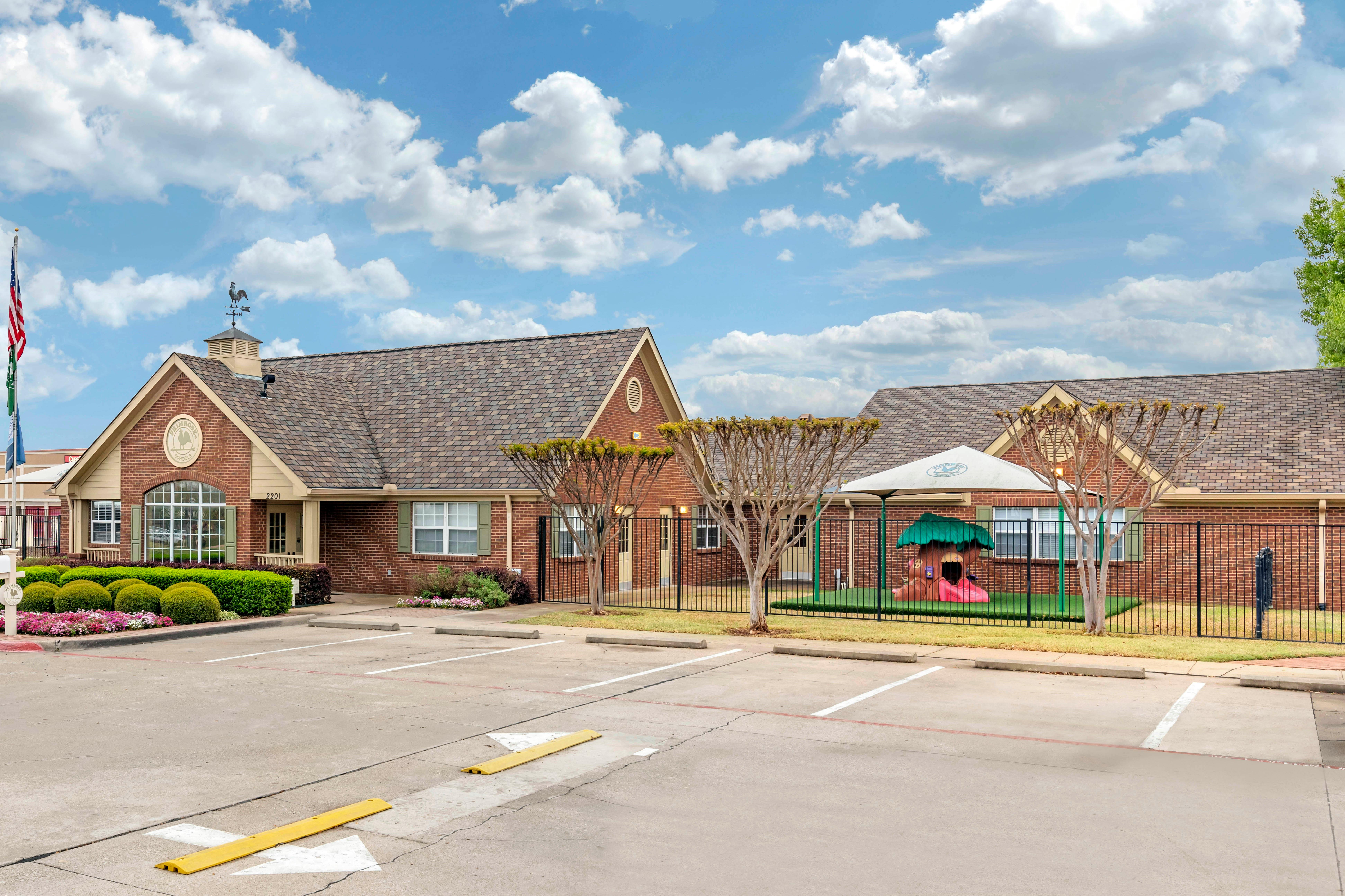 Building exterior with a playground, American flag, and parking lot