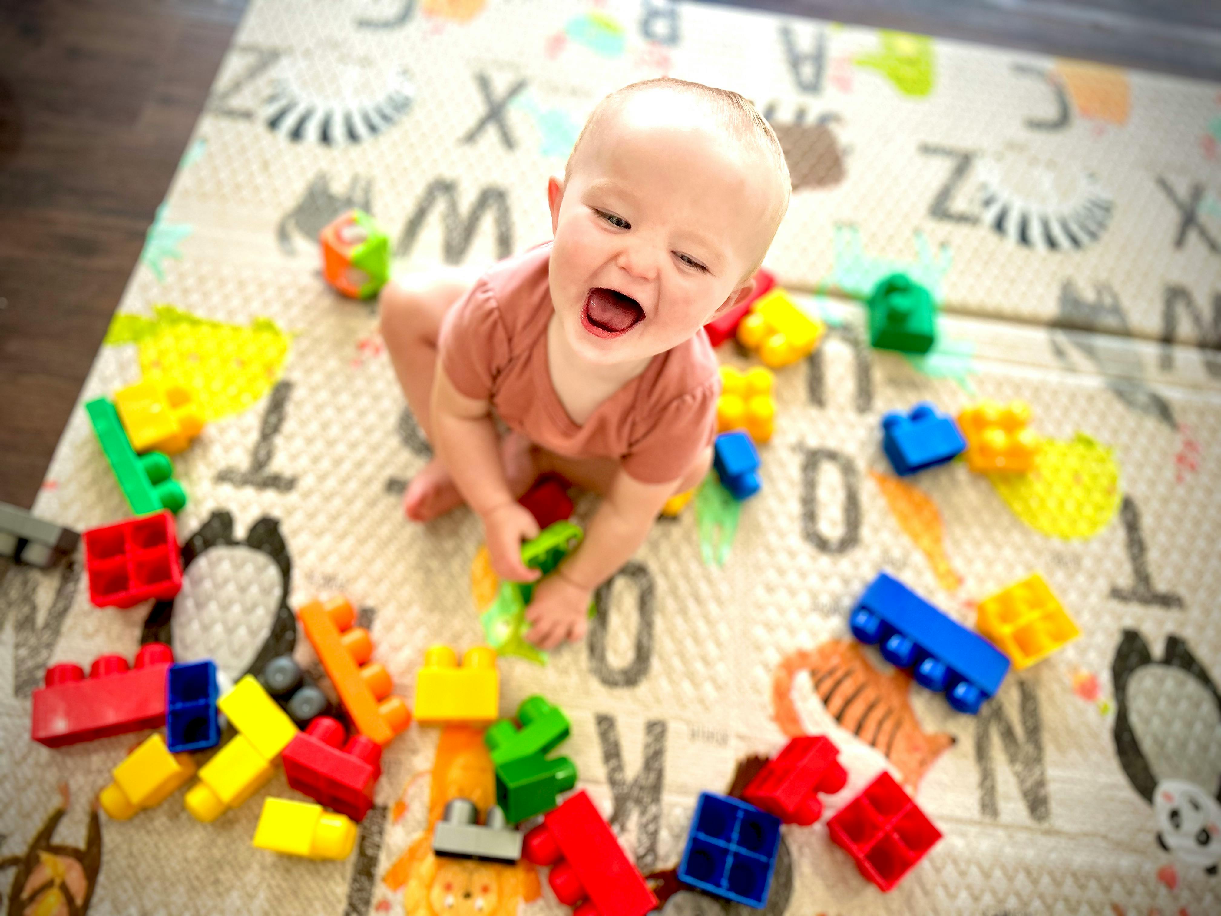 Child playing with colorful building blocks on a playmat