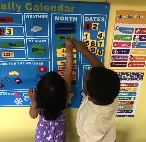 Two children interacting with a daily calendar chart