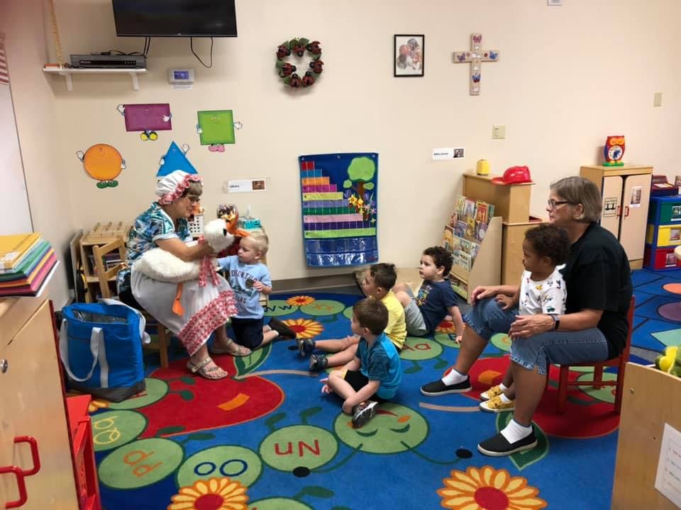 Two adults interacting with children in a classroom setting