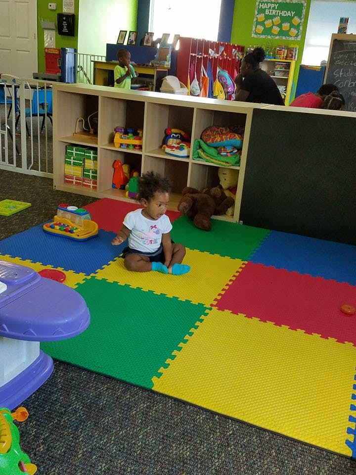 Child sitting on colorful play mats in a classroom