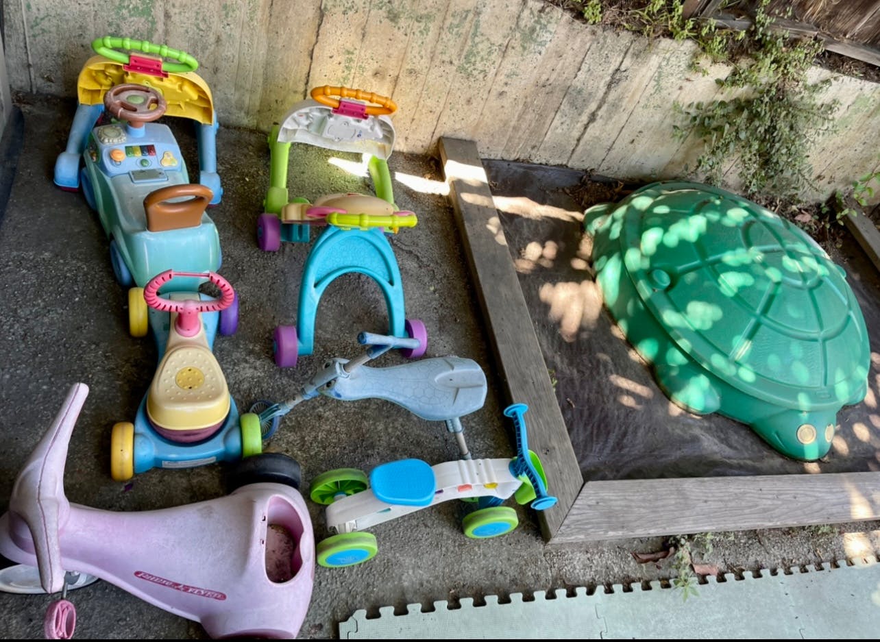 Assortment of children's ride-on toys and a turtle sandbox