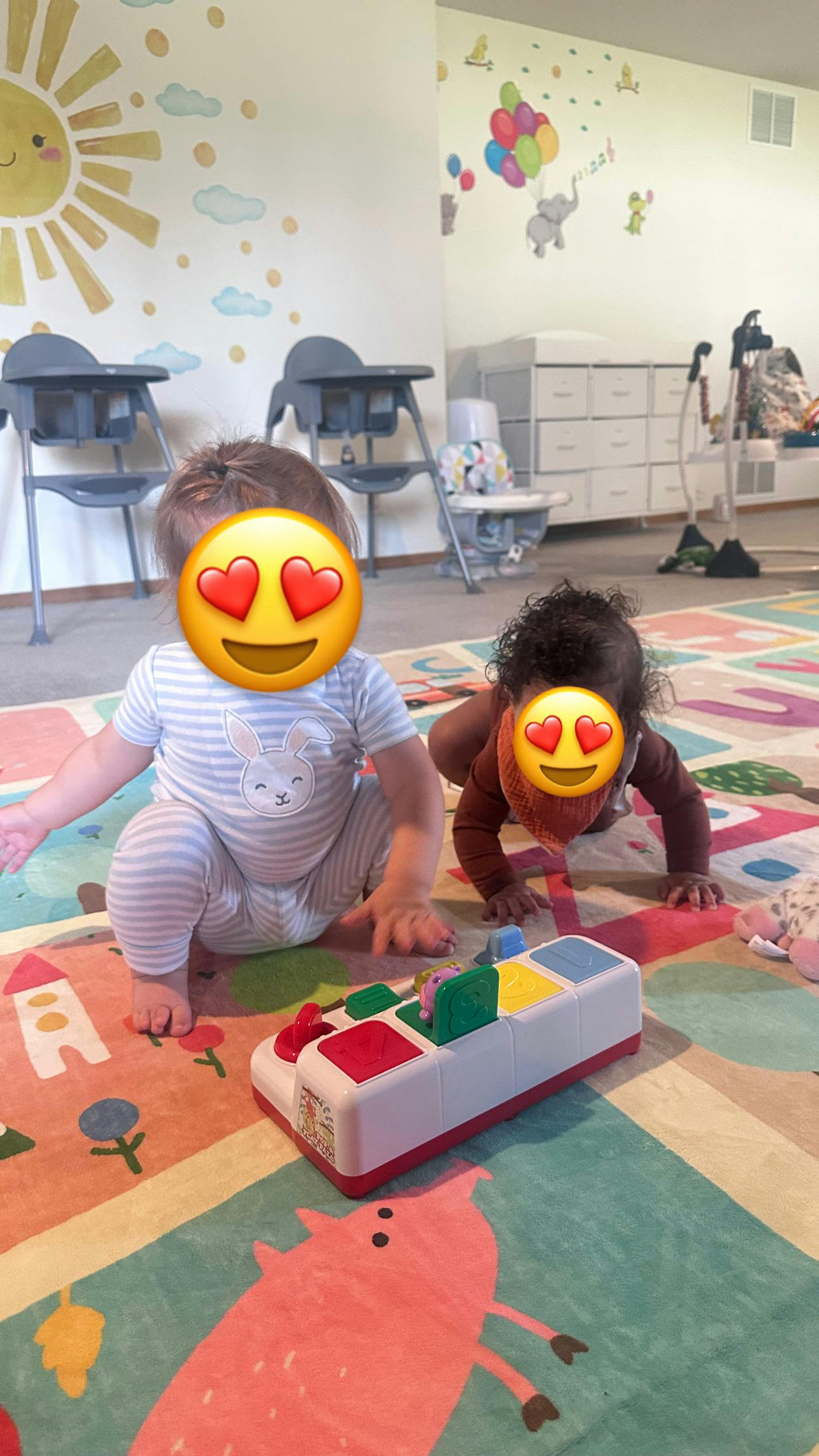 Two children playing with a pop-up toy on a colorful play mat