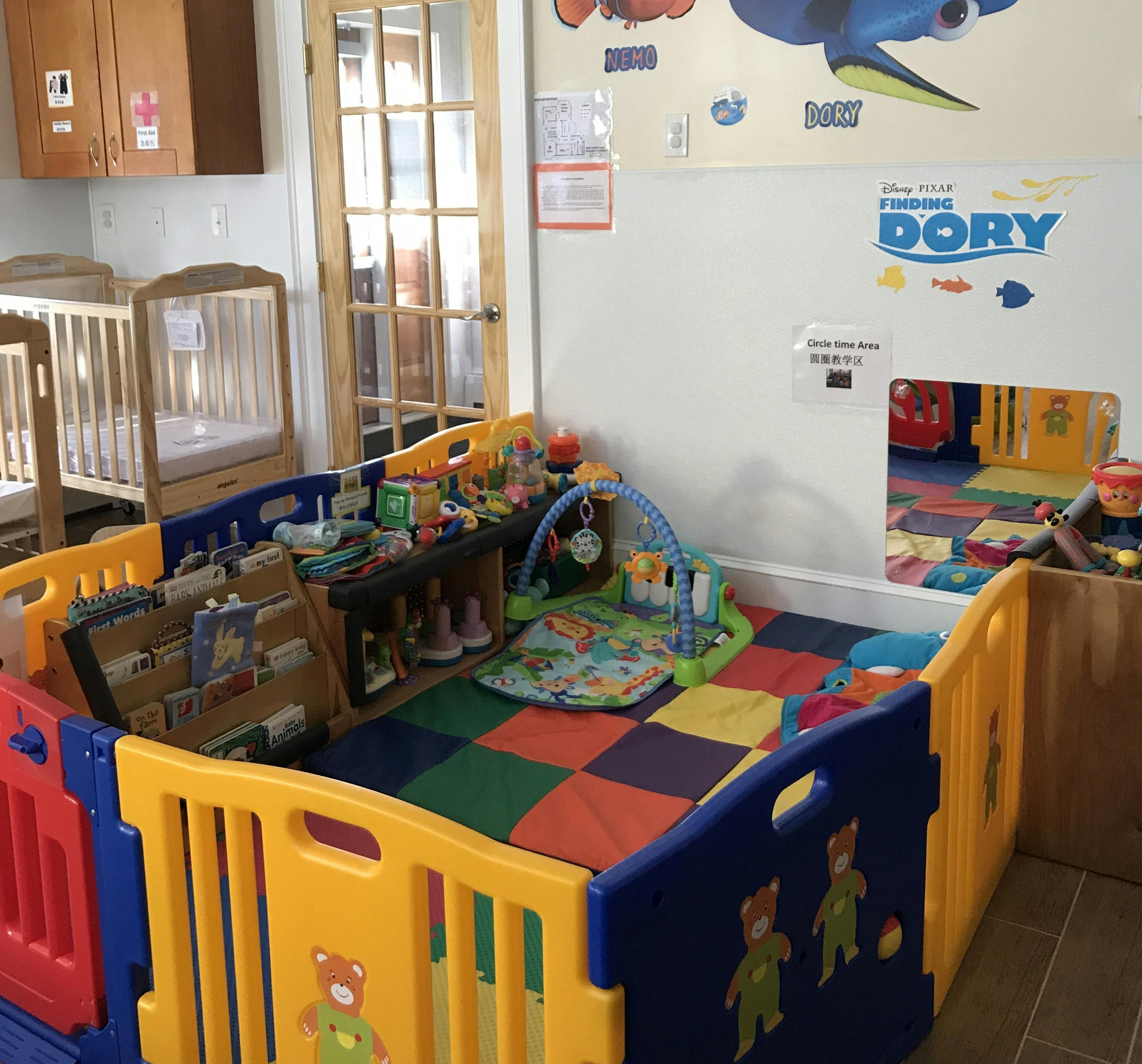 Playpen with colorful floor mats and toys in a room with cribs