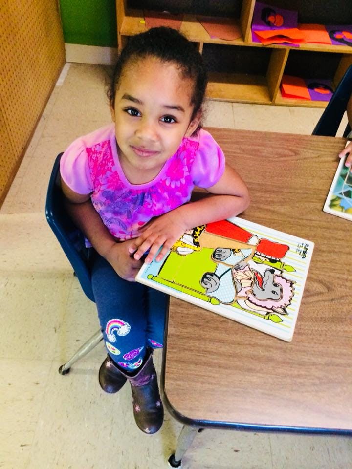 Child sitting at a table with a puzzle