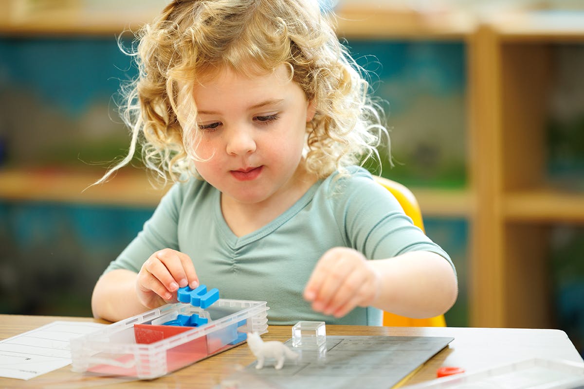 Child playing with small blocks and toys at a table