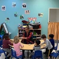 Adult and children sitting around a table in a classroom