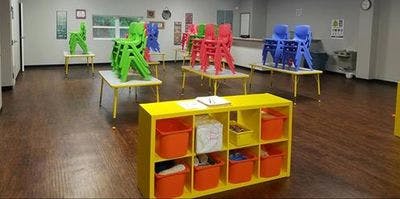 Classroom with small tables and chairs stacked on top