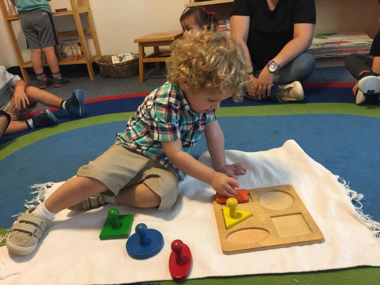 Child playing with a shape sorter puzzle on a white blanket