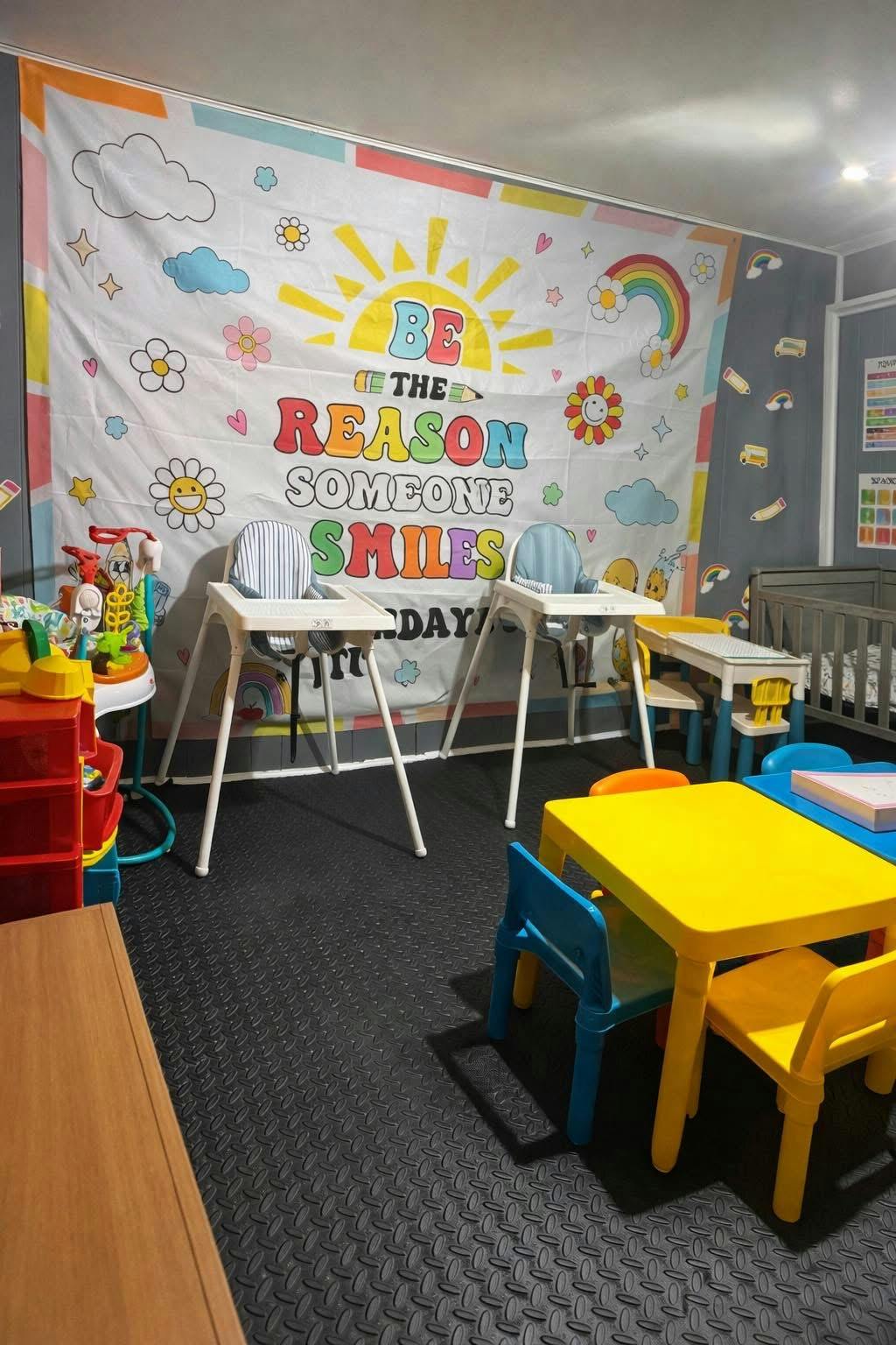 Childcare space with high chairs and colorful small tables in front of a banner