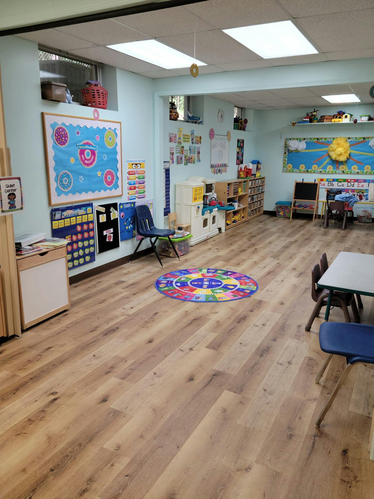 Empty classroom with light blue walls, wooden floor, and colorful decorations