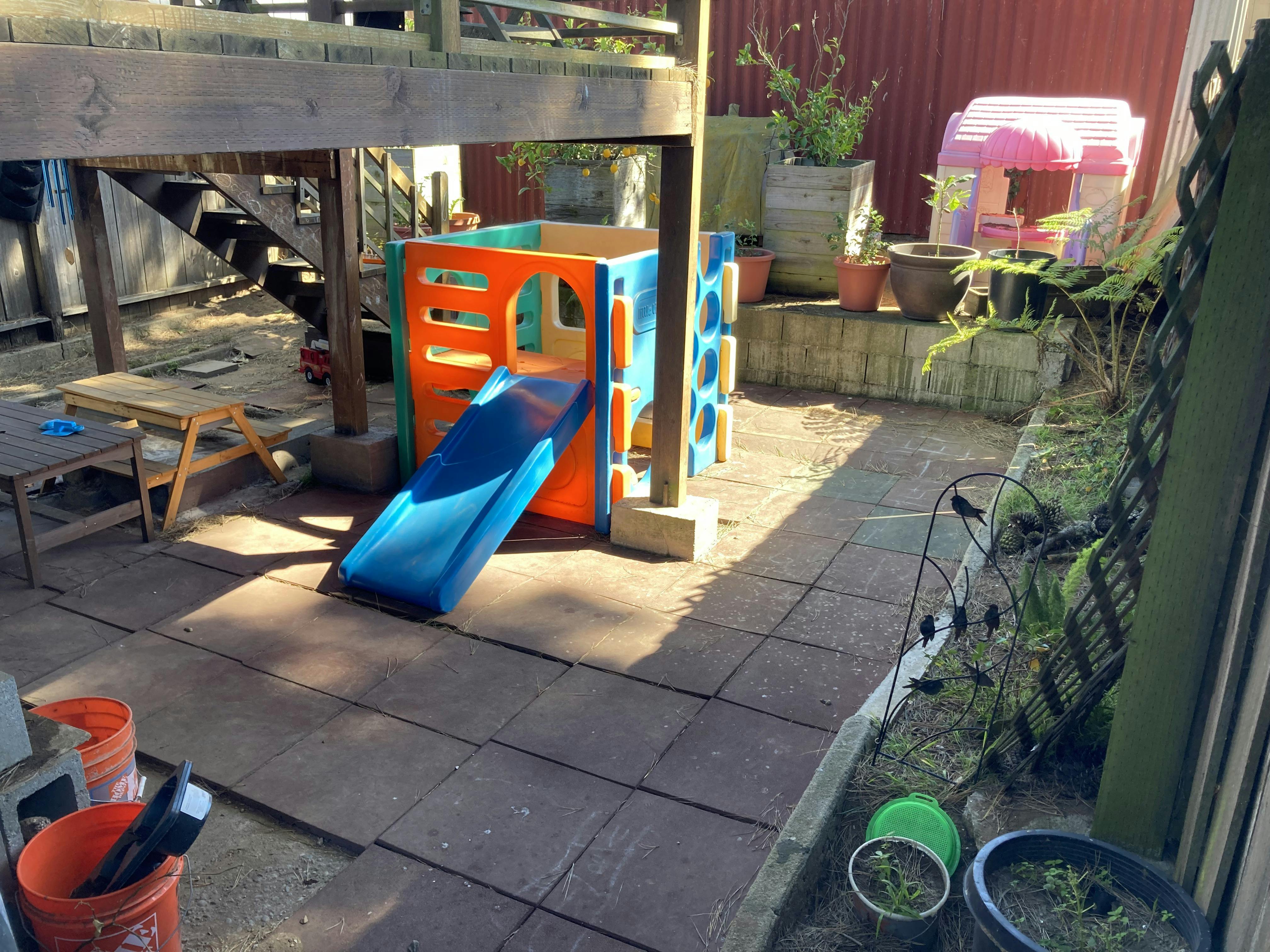 A colorful play structure with a blue slide in a backyard area