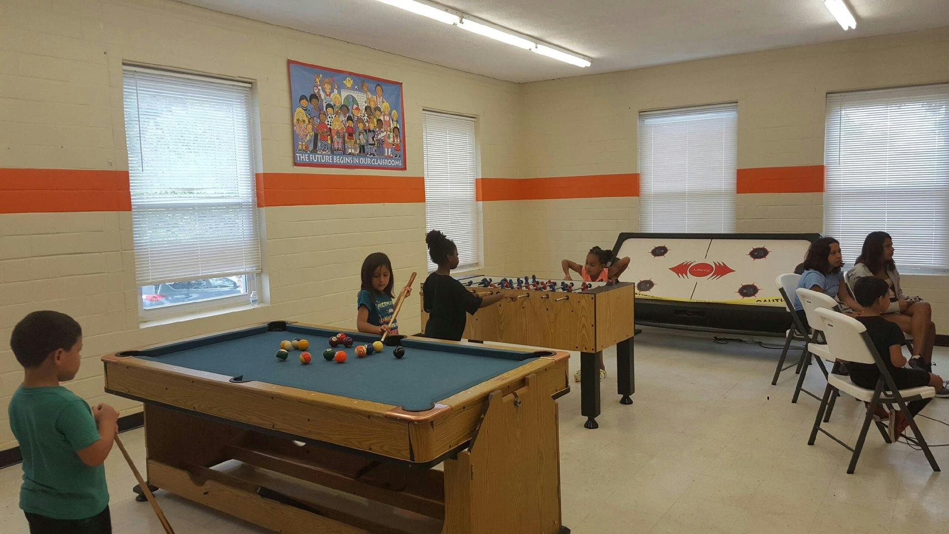 Children playing pool and foosball in a room